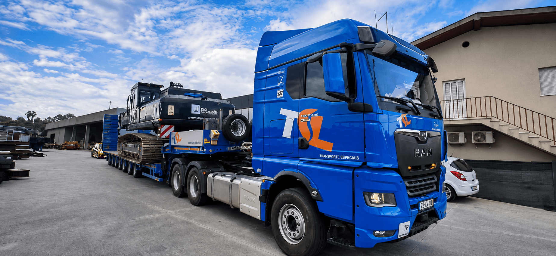 Camião TSL com baixa-cama a transportar máquina pesada